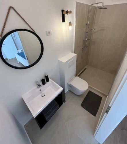 a bathroom with a sink and a mirror and a toilet at Apartment Check in in Pula