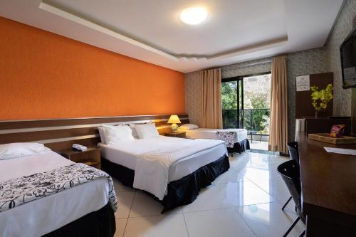 een hotelkamer met 2 bedden en een raam bij Hotel Green Hill in Juiz de Fora