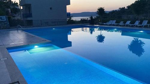 a large blue swimming pool with chairs around it at Semiramis Garden in Milas