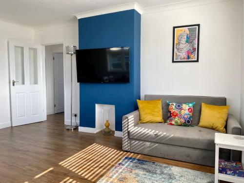 a living room with a couch and a blue wall at Cairo House in Peacehaven