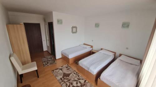 a small room with two beds and a chair at Pensiune Runcu Stone in Runcu