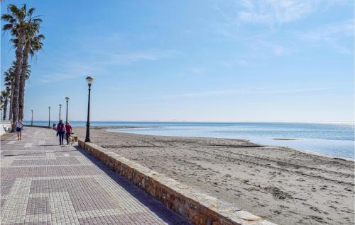people walking on a beach with palm trees and the ocean at Beautiful Home In Los Alcázares in Los Narejos