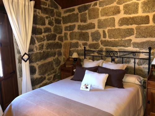 a bedroom with a bed in a stone wall at El Balconcillo del Alberche in Navaluenga