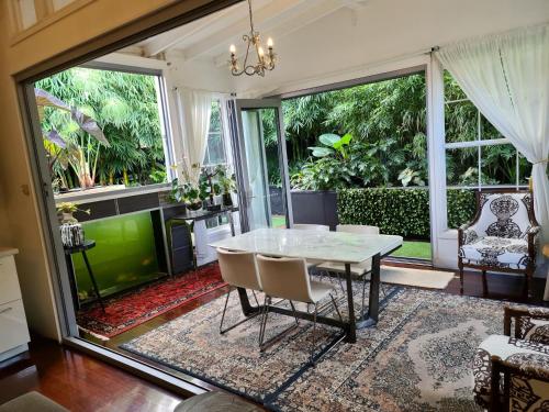 a dining room with a table and chairs and large windows at Bamboo House, Close to the City & Airport & Train station and Brighton Le Sands Beach in Sydney