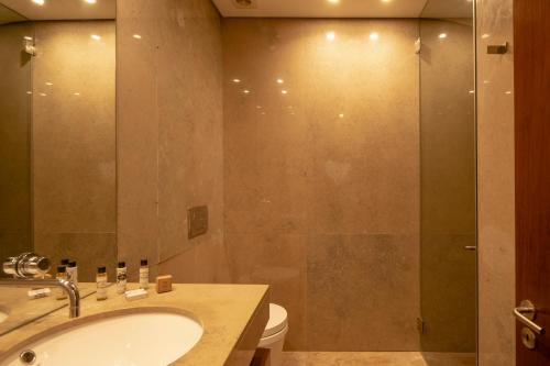 uma casa de banho com um lavatório e uma cabina de duche em vidro. em Tróia Resort Beach Villa em Tróia