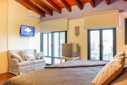 ein Schlafzimmer mit einem Bett, einem Sofa und einem TV in der Unterkunft Villa Orbayu B&B Boutique in Cuernavaca