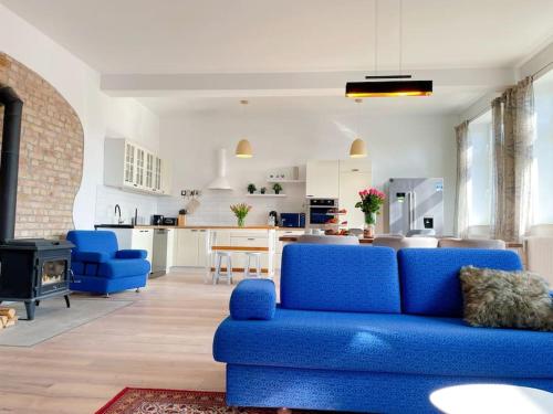 a living room with a blue couch and a kitchen at Landhof in Ganschendorf, Landhaus Seenah in Sarow