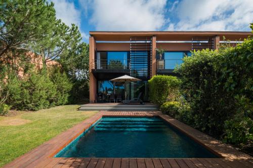 a house with a swimming pool in front of a house at Tróia Resort Beach Villa in Troia