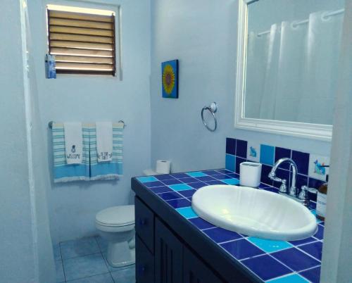 a blue tiled bathroom with a sink and a toilet at Seascape Villa 3BR with Stunning Caribbean Sea View in Castries