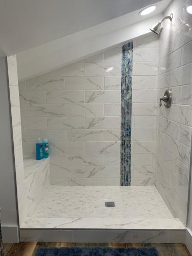 La salle de bains est pourvue d'une douche et de murs en marbre blanc. dans l'établissement Oasis in Ocean Ridge, Walk to the Beach, à Boynton Beach