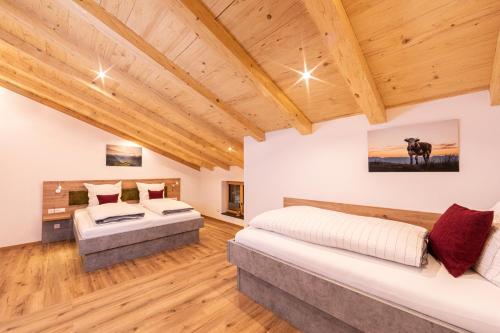 two beds in a room with wooden ceilings at Haus Unterstöberl in Bischofswiesen