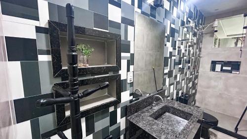 a bathroom with a black and white checkered wall at Casa Lunna Paraty - Praia e cachoeira in Paraty