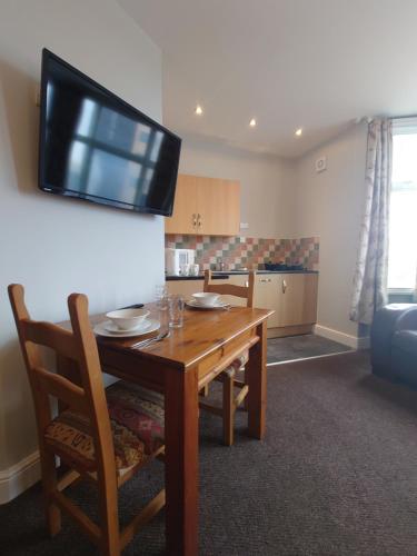 a kitchen with a wooden table with a television on the wall at Pier View Apartments by Pillow Partners in Skegness