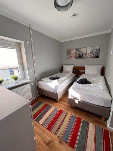two beds in a small room with a rug at FineApartment Borgstedt in Borgstedt
