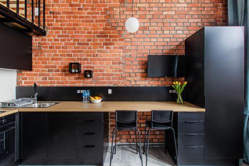 a kitchen with black cabinets and a brick wall at Smart Rental Management Apartments in Wrocław