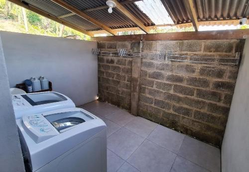 a washing machine in a room with a brick wall at Ipê Eco Village in Penha