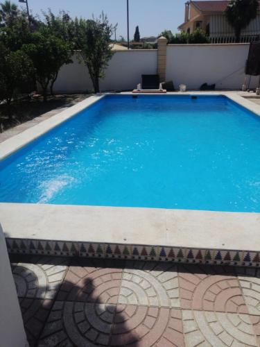 a large blue swimming pool next to a white wall at Villa Loma in Belicena