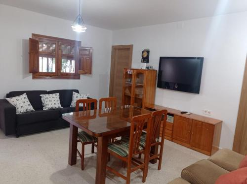sala de estar con mesa, sillas y TV en Villa Loma en Belicena
