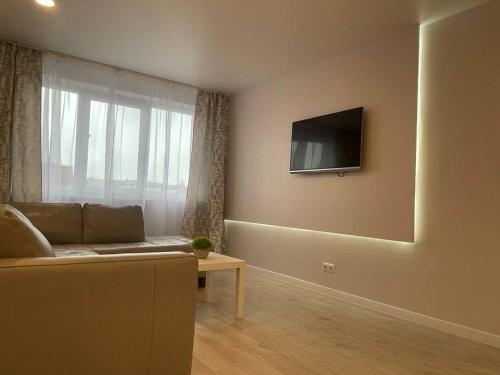 a living room with a couch and a television on the wall at Klaipeda Center Apartment in Klaipėda