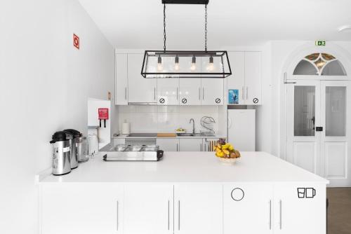 a kitchen with white cabinets and a white counter top at Ínsua Hostel in São Pedro do Sul