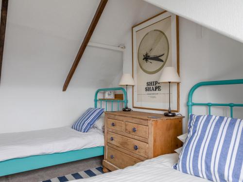 ein Schlafzimmer mit 2 Betten und einer Uhr an der Wand in der Unterkunft Bumblebee Cottage in Salcombe