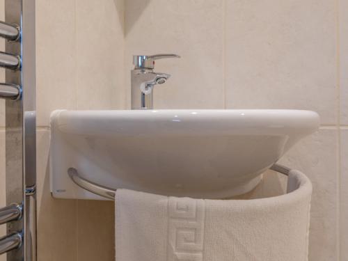 a white sink in a bathroom with a towel at Bumblebee Cottage in Salcombe