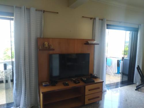 uma sala de estar com uma televisão de ecrã plano e um centro de entretenimento em Apartamento charmoso em Saquarema