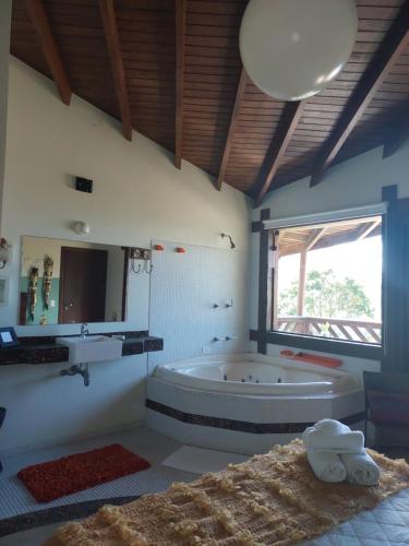 La grande salle de bains est pourvue d'une baignoire et d'une fenêtre. dans l'établissement Secret View Suítes, à Ubatuba