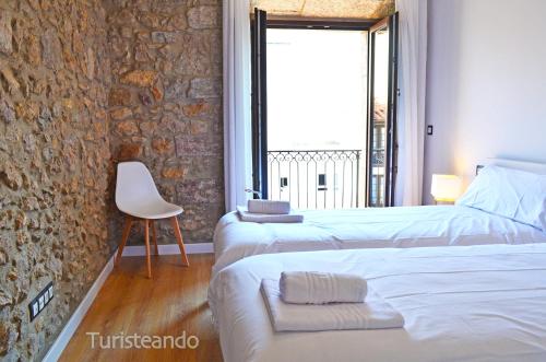 two beds in a room with a stone wall at Apartamento Llerandi 2B - Totalmente reformado y con balcón al corazón de San Vicente de la Barquera in San Vicente de la Barquera