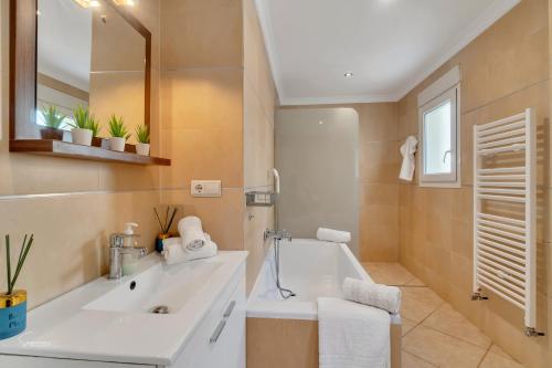 Un baño con bañera blanca y lavabo. en Mariposa Blanca, en Moraira