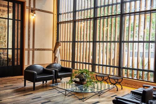 a living room with a couch and chairs and large windows at Austin Proper Hotel, a Member of Design Hotels in Austin