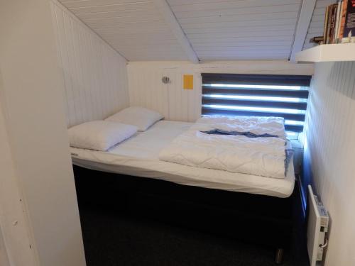 een klein bed in een kleine kamer met een raam bij Holiday Home M&A in Toftlund