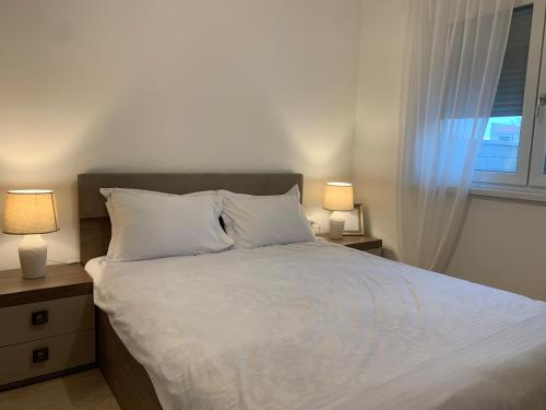 a bedroom with a large white bed with two lamps at DUO Residence in Dumbrăviţa