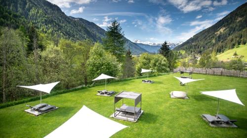 a group of chairs and umbrellas on a grass field at La Casies Mountain Hotel in Santa Maddalena in Casies