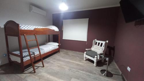 sypialnia z 2 łóżkami piętrowymi i krzesłem w obiekcie Casa con Piscina y Parrilla w mieście Garupá