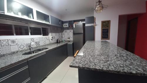 a kitchen with granite counter tops and a refrigerator at Casa con Piscina y Parrilla in Garupá