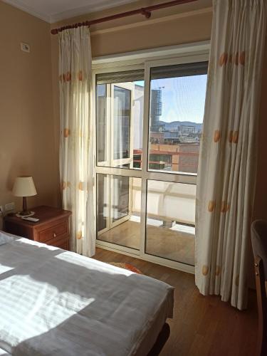 een slaapkamer met een bed en een groot raam bij Home Sweet Rental in Tirana