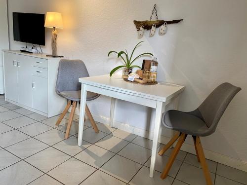 a white desk and two chairs in a room at Kajüthus Apartment 6 in Fehmarn
