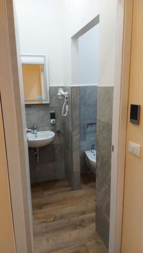 een badkamer met een wastafel, een toilet en een spiegel bij Glam Resort G H O S T E L in La Spezia