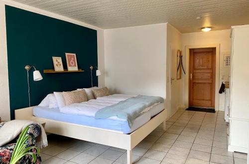 a bedroom with a large bed with a green wall at Kajüthus Apartment 6 in Fehmarn