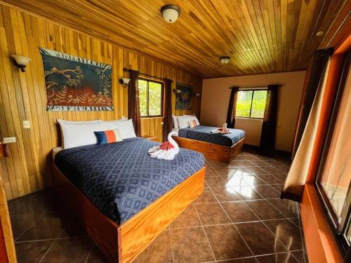 two beds in a room with wooden walls at TucanTico Lodge ~ Casa # 3 in Monteverde Costa Rica