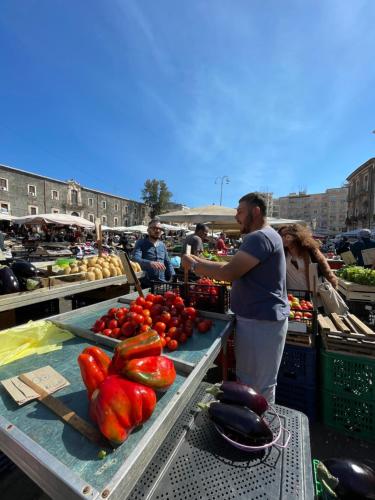 a man standing in front of a market with vegetables at Gli appartamenti di Agata in Catania
