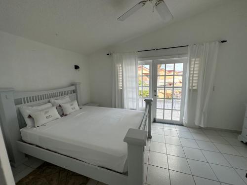 a white bedroom with a white bed and a window at Antigua chiama Italia villas in Jolly Harbour