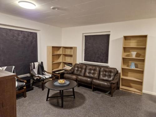 a living room with a leather couch and a table at Guest House Rens in Bylderup-Bov