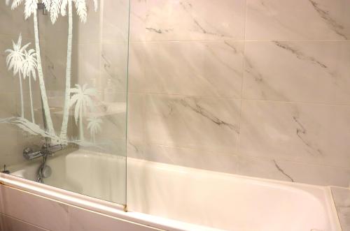 bagno con vasca e porta doccia in vetro. di Sunrise Apartmento Ribeira d'Ilhas Ericeira a Ericeira