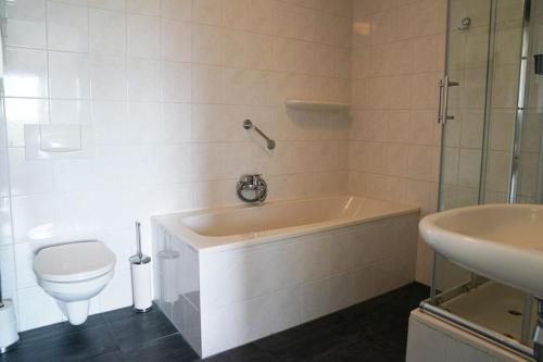 een badkamer met een bad, een toilet en een wastafel bij Vakantieboerderij Huize Nuis in Noordbeemster