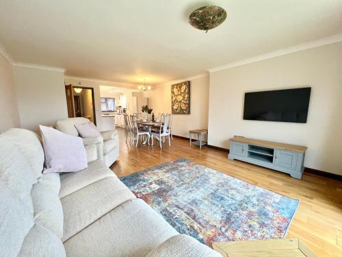 ein Wohnzimmer mit einem weißen Sofa und einem Flachbild-TV in der Unterkunft 3 Bedroom house - Sandown in Sandown