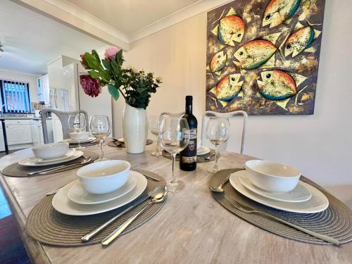 a dining room table with plates and wine glasses at 3 Bedroom house - Sandown in Sandown