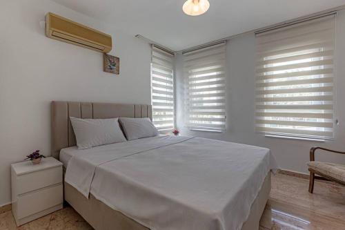 a bedroom with a large white bed and windows at Güneş Villa in Antalya