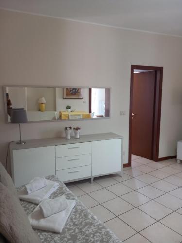 Habitación blanca con cama y espejo en Appartamento al Battistero, en Oggiono